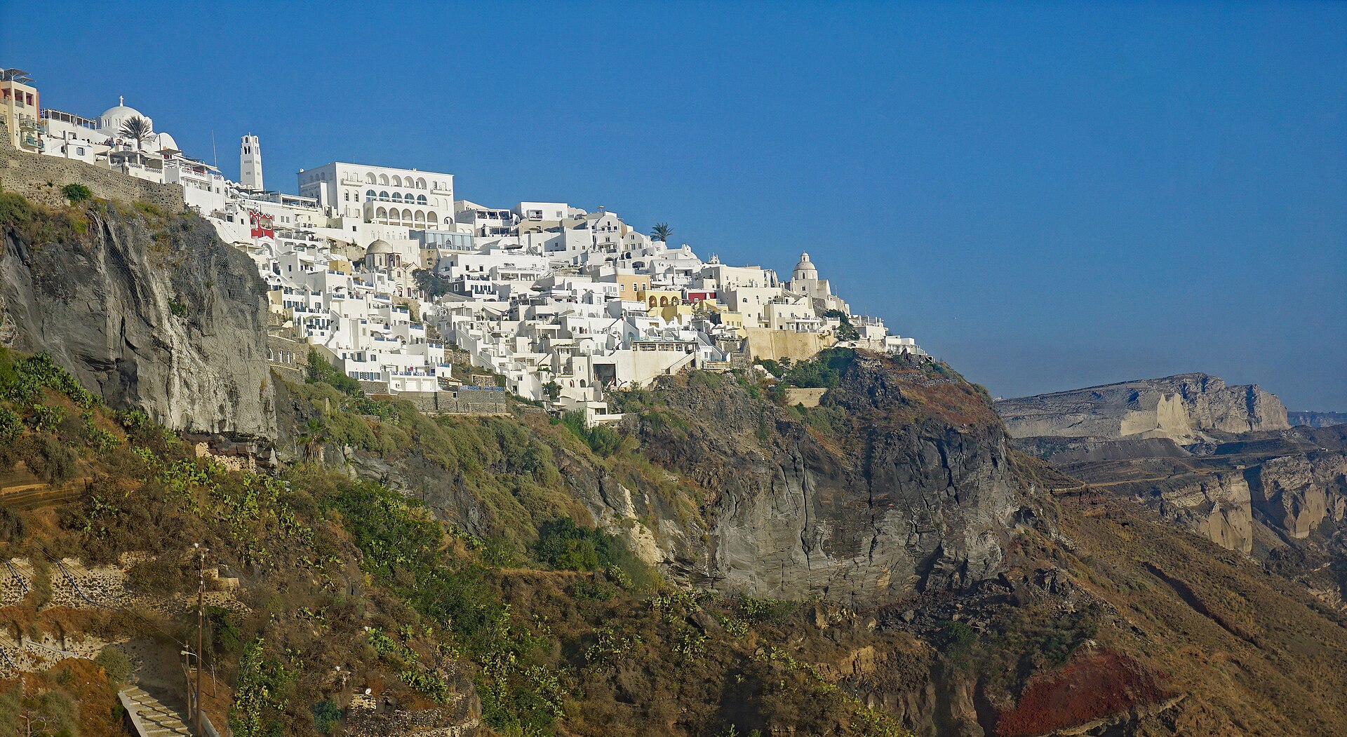 Whitewashed Fira spreading across Santorini's dark volcanic cliffs above the caldera