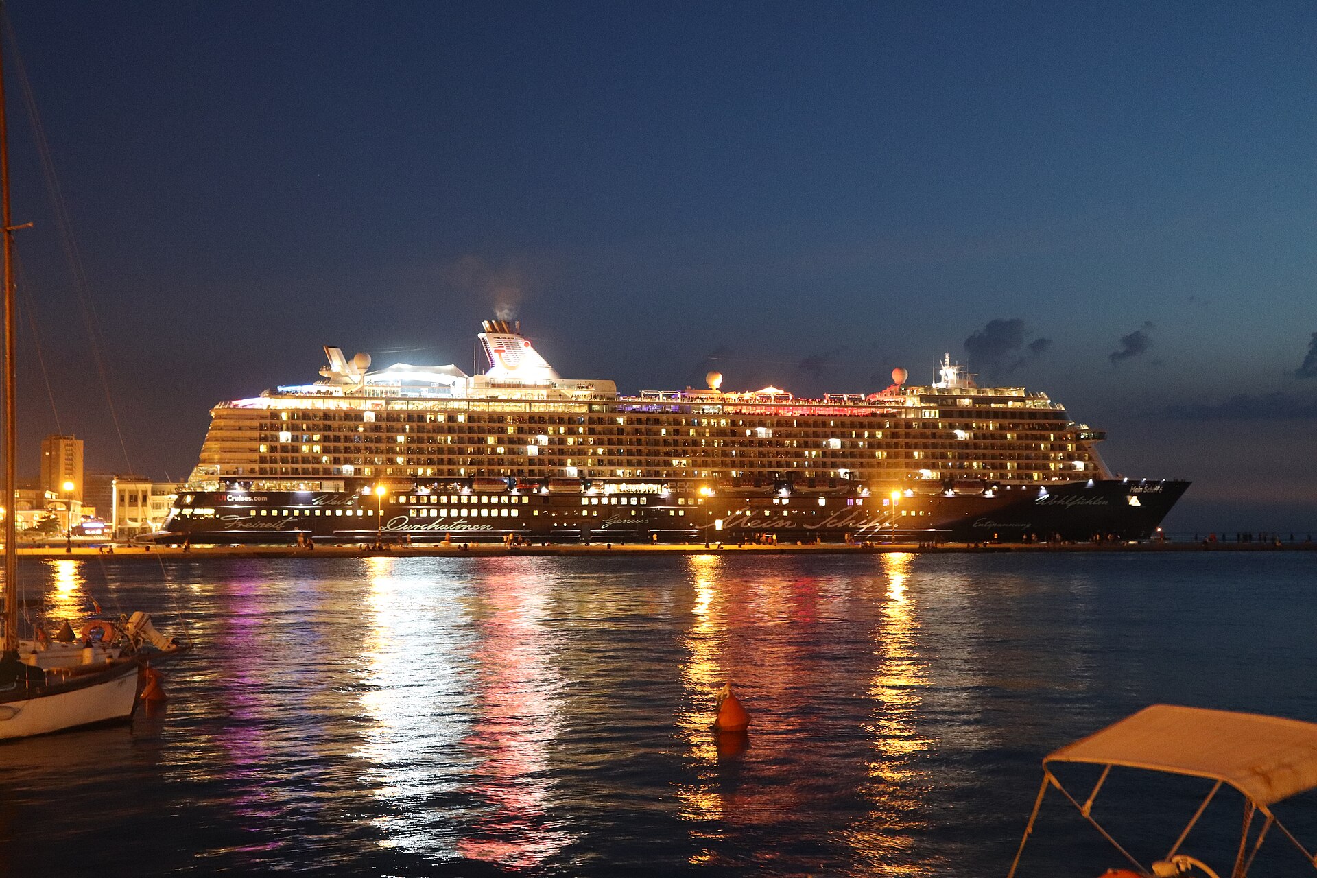 Mein Schiff 6 illuminated at a Trieste waterfront cruise berth at night