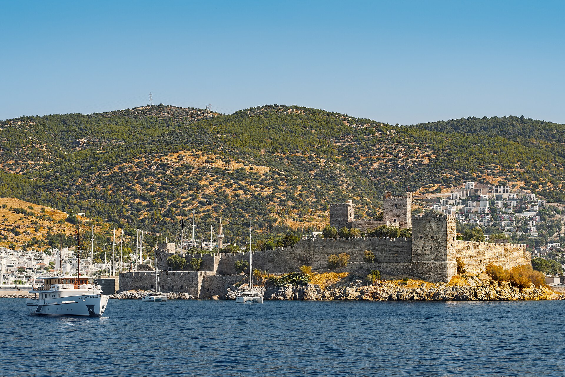 Stone towers and walls of Bodrum Castle rising beside the blue Aegean harbor