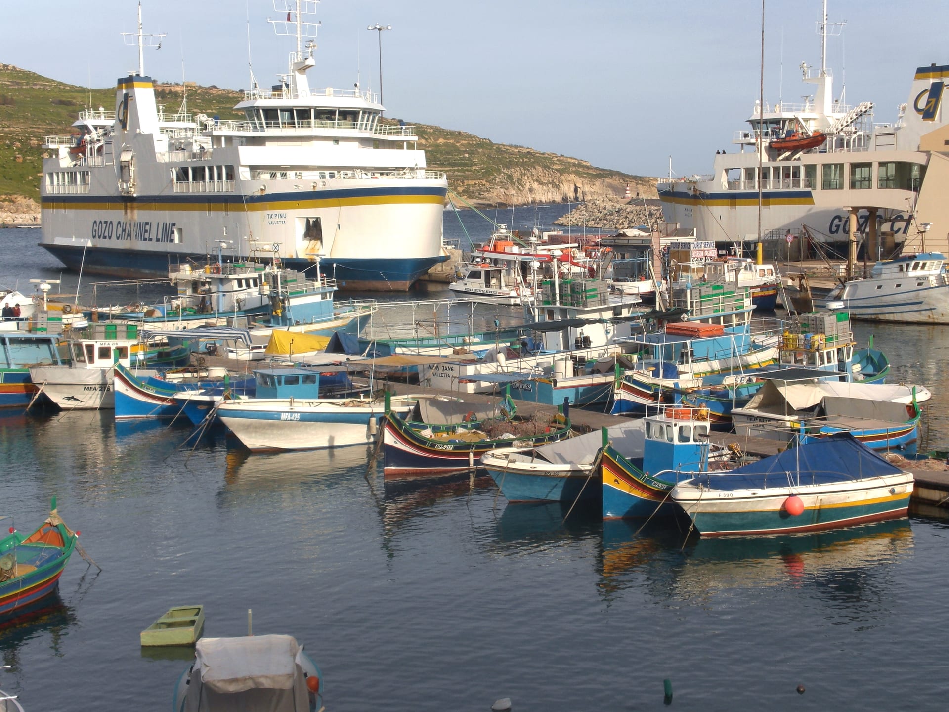 Gozo Channel ferries and colorful fishing boats inside Mġarr Harbour on Gozo