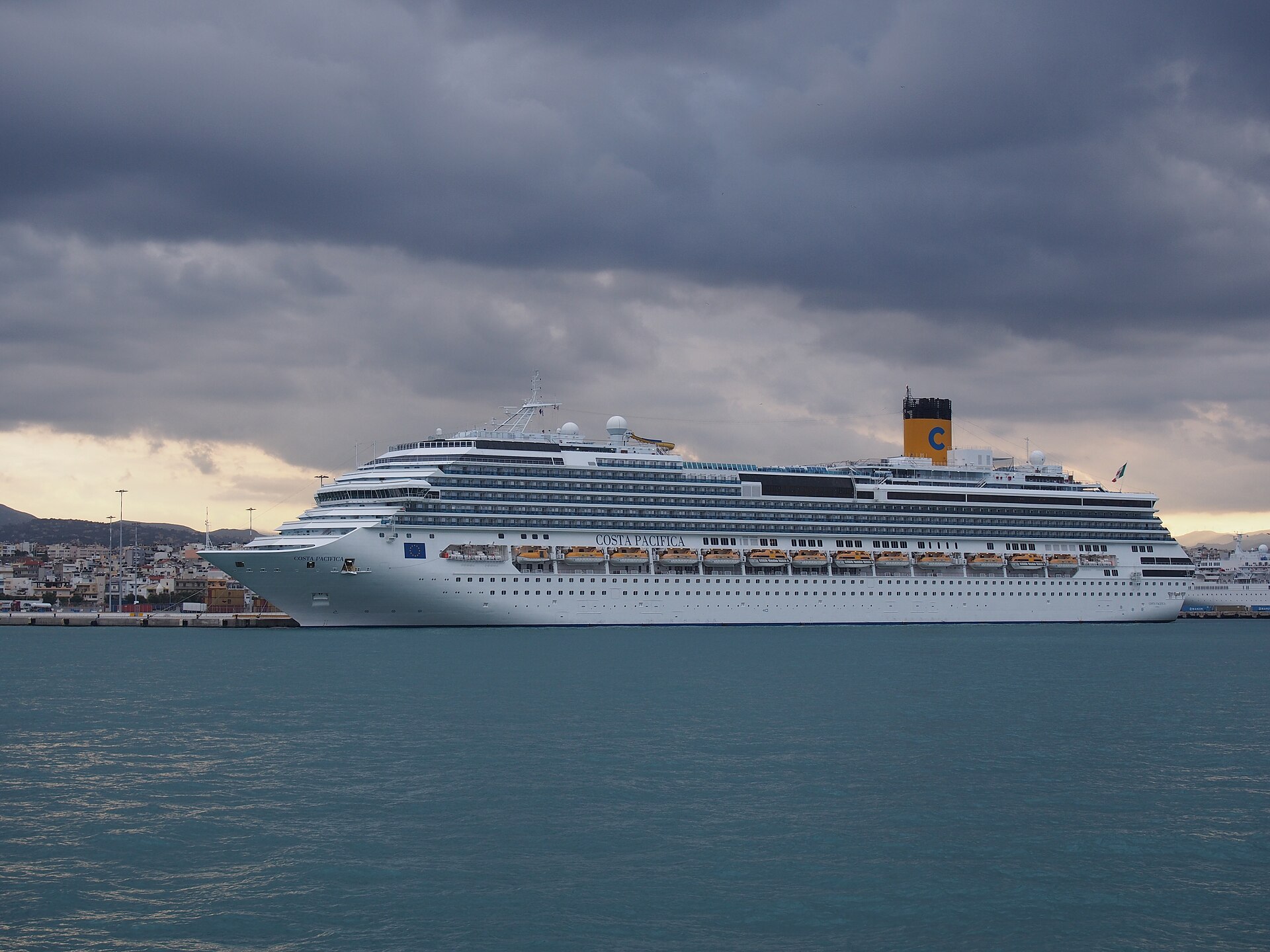 Cruise ship berthed across the water at Heraklion port beneath a clouded Cretan sky